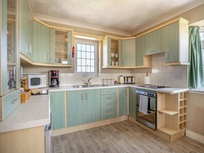A kitchen with light green cabinets, a microwave, a toaster, and a sink.