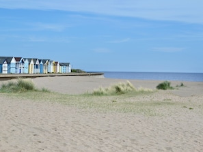 A beach with a row of colorful beach huts and a sandy beach.