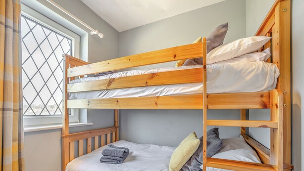 Ein Stockbett mit Fenster, Holz Kopfteil und einer kleinen Ablagefläche.