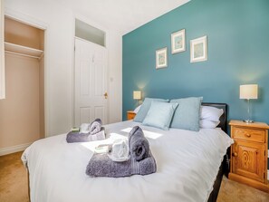 A hotel room with a bed, two bedside tables, a wardrobe, and three framed pictures on the wall.