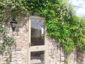 A stone wall with a wooden door and a lantern. - 0 bedroom accommodation in Edge Hills, near Littledean (Edge Hills, near Littledean)