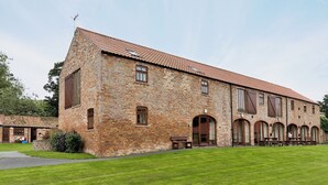 A large brick building with a tiled roof, multiple windows, and a grassy courtyard. - 2 bedroom accommodation in Filey (Filey)