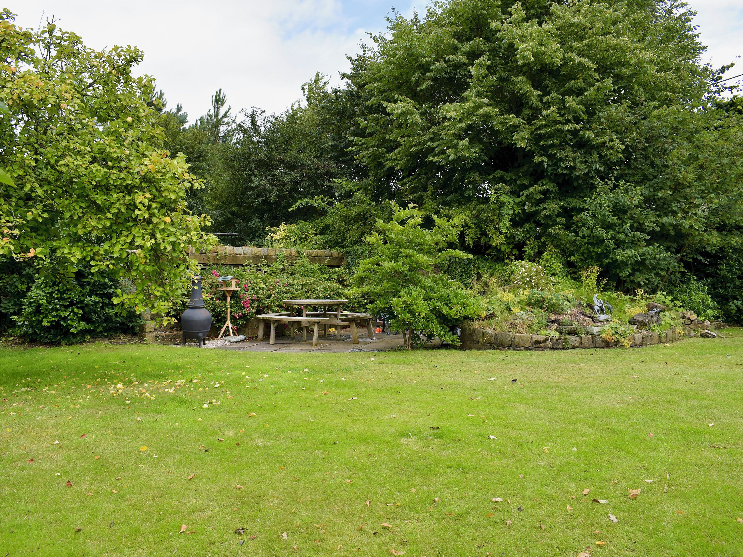 A garden with a picnic table and a bird feeder.