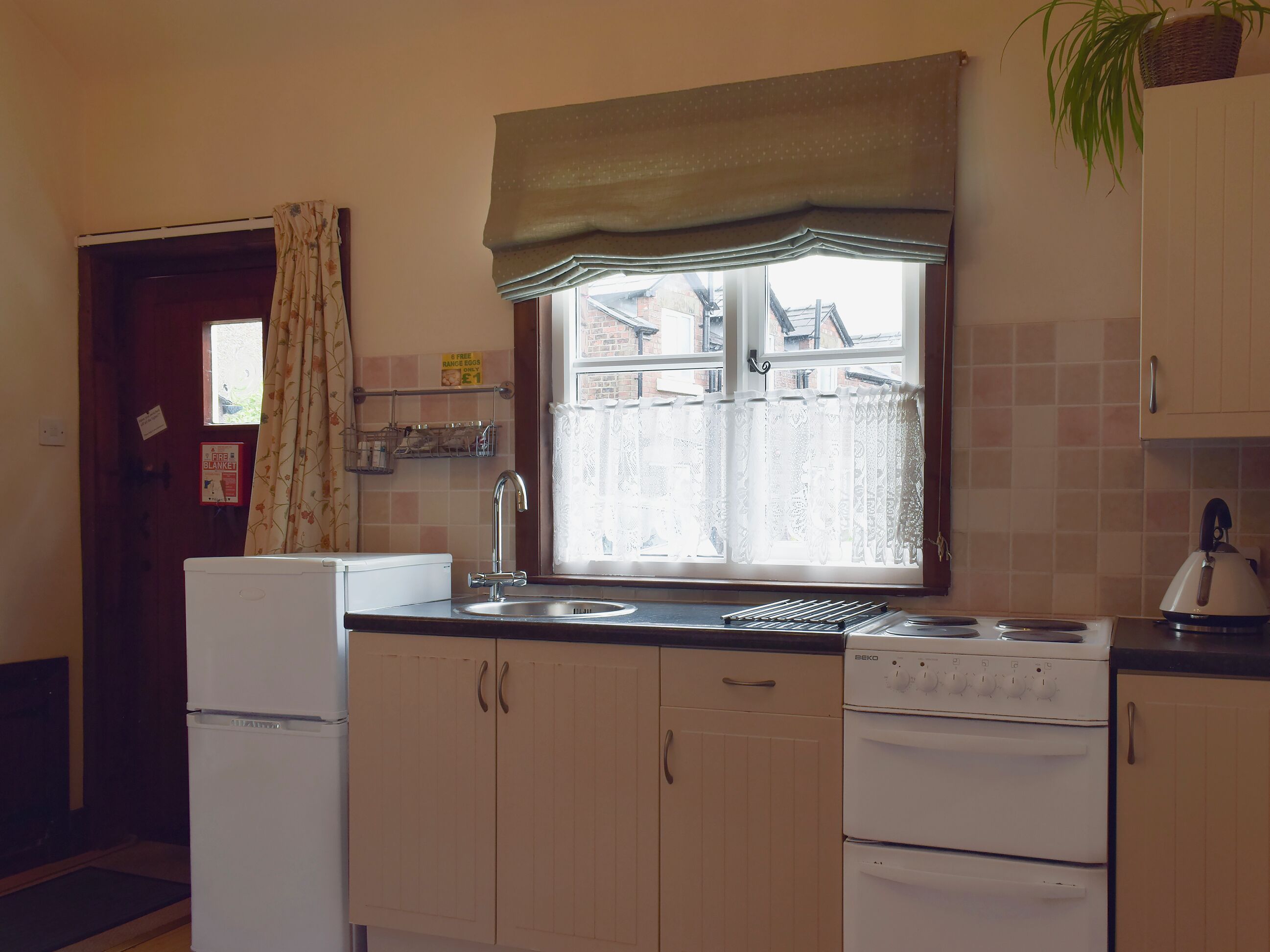 A compact kitchen with a refrigerator, sink, stove, and cabinets.