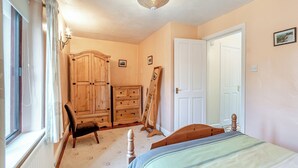 A bedroom with a bed, a wooden wardrobe, a dresser, a chair, and a door. - 2 bedroom accommodation in Darley Bridge, near Matlock (Darley Bridge, near Matlock)