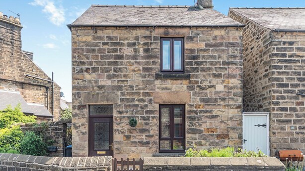A stone building with a traditional design, featuring a dark wooden door, a window with a white frame, and a small garden area with a wooden fence. - 2 bedroom accommodation in Darley Bridge, near Matlock (Darley Bridge, near Matlock)