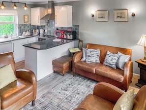 A modern kitchen with a central island, a brown leather sofa with patterned cushions, and a wooden floor. - 2 bedroom accommodation in Holt (Holt)