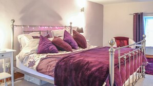 A neatly made bed with a metal frame, a bedside table, and a lamp.