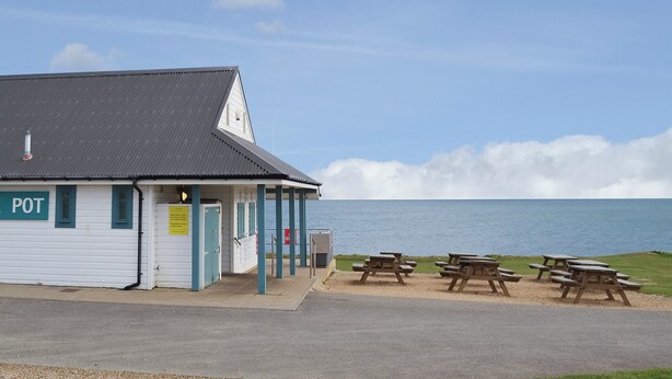 A white building with a sign reading "POT" and a view of the sea.