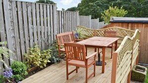 A wooden deck with a table and chairs, surrounded by a wooden fence and various plants. - 2 bedroom accommodation in Cutthorpe, near Chesterfield (Cutthorpe, near Chesterfield)