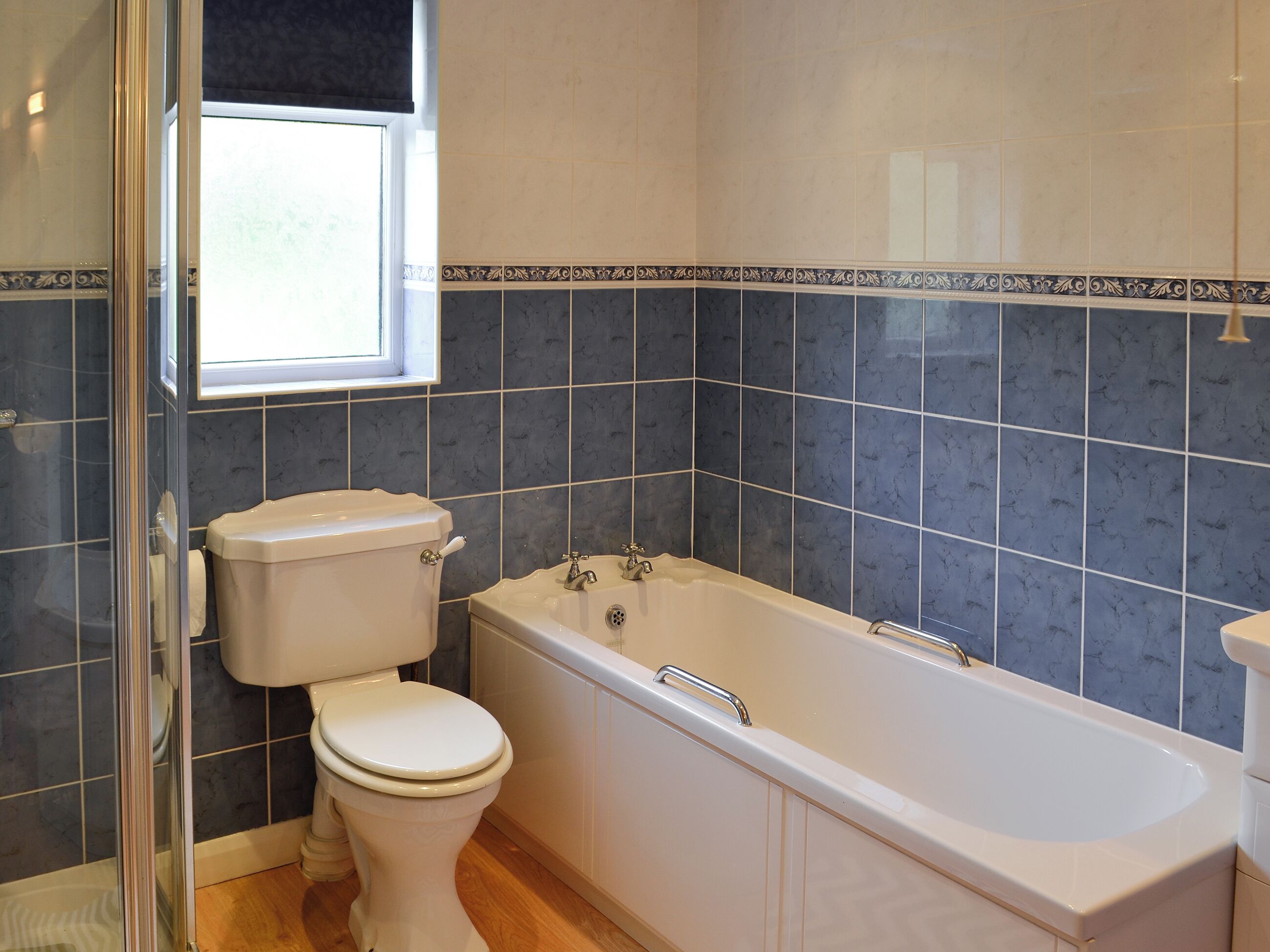 A bathroom with a toilet, bathtub, and a window.