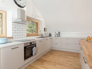 A modern kitchen with white cabinets, a built-in oven, a kettle, and a coffee maker.