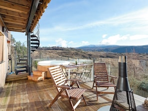 A wooden deck with outdoor seating, a hot tub, and a view of mountains.