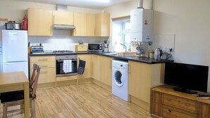 Une cuisine compacte équipée des appareils essentiels, tels qu’un four à micro-ondes, une cuisinière, un four et un lave-linge.