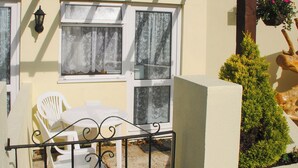 Ein Balkon mit einem weißen Tisch und Stühlen, einem Metallgitter und einem kleinen Blumentopf.