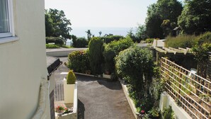 Ein Innenhof mit Blumentöpfen, ein kleiner Garten und Blick aufs Meer.