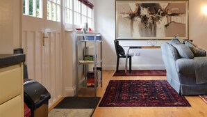 A living room with a sofa, a rug, a bookshelf, and a painting on the wall.