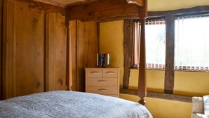 A bedroom with a wooden bed frame, a wooden dresser, and a wicker chair. - 2 bedroom accommodation in Knapton Green, near Leominster (Knapton Green, near Leominster)