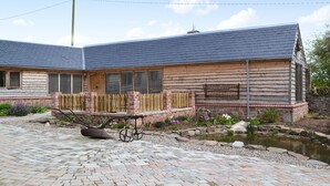 A log cabin-style building with a sloped roof, a wooden fence, and a small pond. - 2 bedroom accommodation in Knapton Green, near Leominster (Knapton Green, near Leominster)