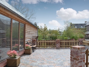 A patio with a brick floor, a wooden fence, and a bench.