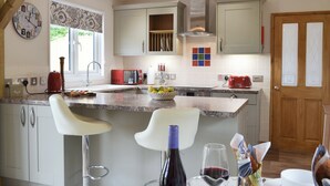 Una cocina moderna con una isla central, taburetes de bar, un tostador rojo y una ventana con vistas.