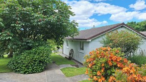 Une maison avec un chemin pavé menant à la porte d’entrée, entourée d’une végétation luxuriante et de plantes en fleurs.