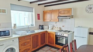 Une cuisine compacte avec des meubles en bois, un four encastré, un four à micro-ondes et un lave-linge.