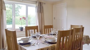 A dining room with a table set for four, a window with curtains, and a door in the background. - 3 bedroom accommodation in Frostenden, near Beccles (Frostenden, near Beccles)