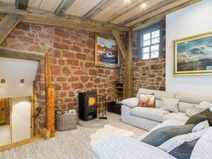 A cozy room with a stone wall, a fireplace, a sofa, and a painting.