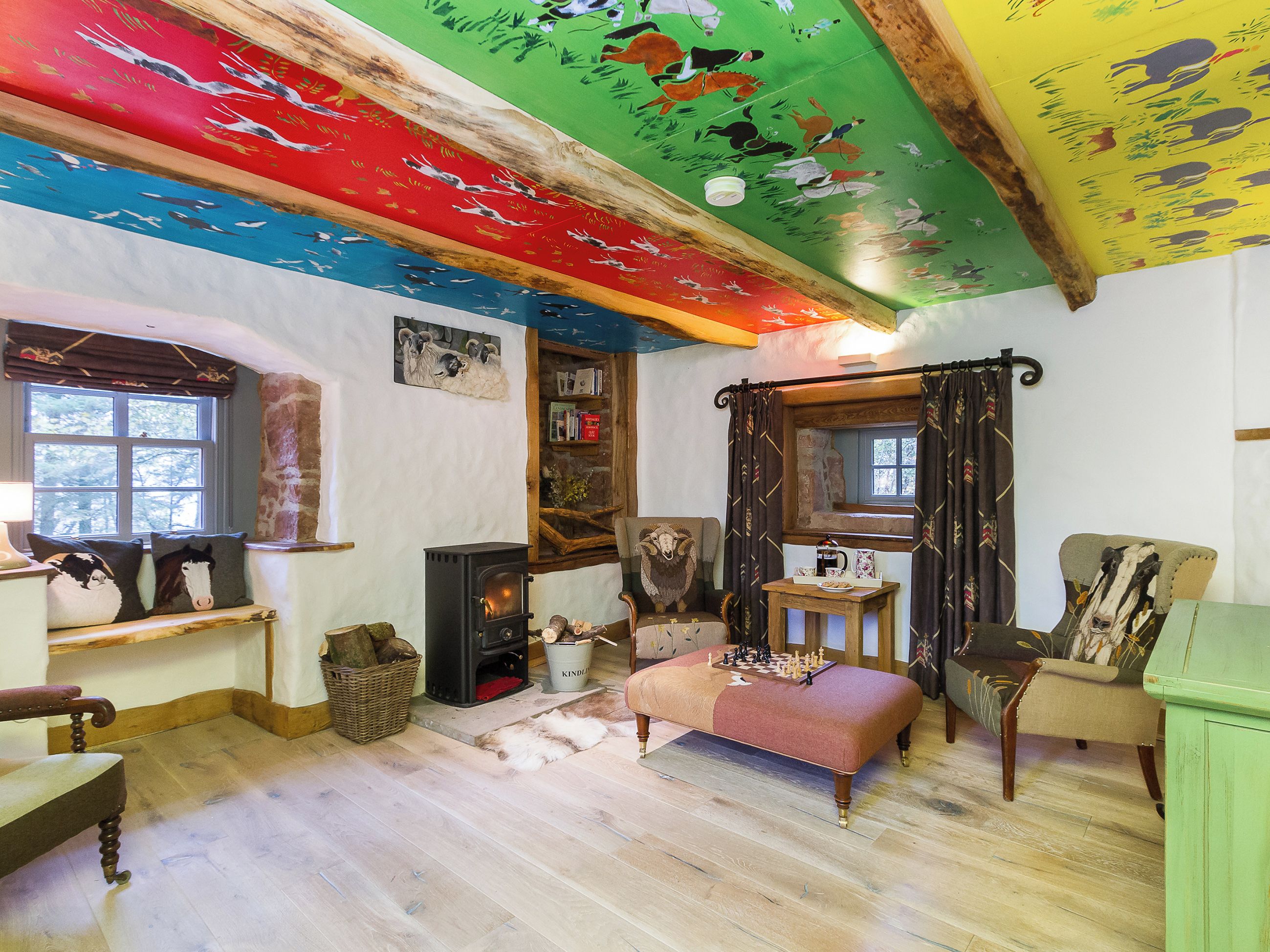 Une pièce chaleureuse avec une cheminée, un canapé, un plancher en bois et un plafond aux couleurs vives.