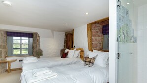 A bedroom with two beds, a window, a wooden bench, and a glass shower enclosure. - 4 bedroom accommodation in Largs (Largs)