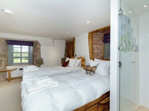A bedroom with two beds, a window, a wooden bench, and a glass shower enclosure. - 4 bedroom accommodation in Largs (Largs)
