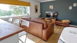 Ein modernes Wohnzimmer mit einer Couch, einem Fernseher und einem Essbereich.