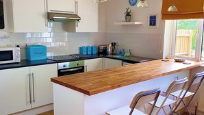 Eine moderne Küche mit weißen Schränken, einer Holz Arbeitsplatte und Barhocker.