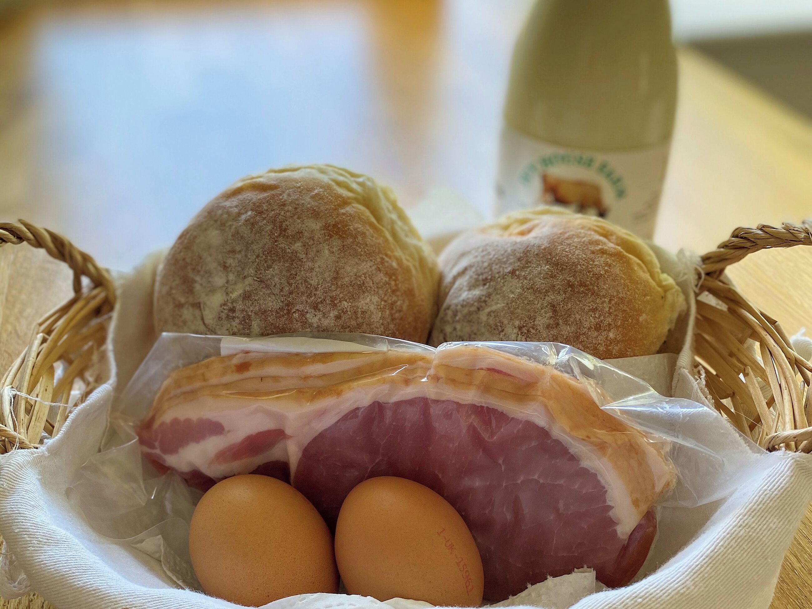 A basket containing bread, a ham, and eggs.
