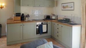 A compact kitchen with a built-in oven, a sink, and a countertop with various appliances. - The perfect hideaway for two. (Salwayash, near Bridport)