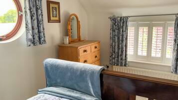 Un dormitorio con cama, cómoda, espejo y ventana con cortinas.