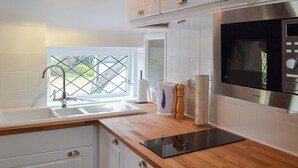 A modern kitchen with white cabinetry, a stainless steel microwave, and a wooden countertop. - 1 bedroom accommodation in Betley, near Nantwich (Betley, near Nantwich)