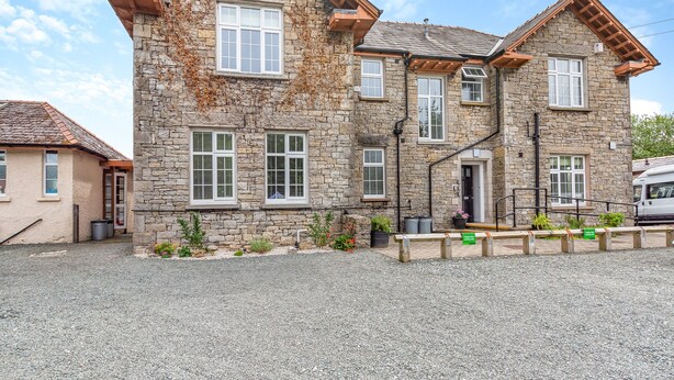A stone building with multiple windows, a gravel driveway, and a parked vehicle. - 2 bedroom accommodation in Meathop, near Grange-over-Sands (Meathop, near Grange-over-Sands)