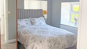 Un dormitorio con cama, ventana con persianas, radiador y lámpara.