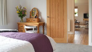 Un dormitorio con cama, cómoda, espejo y puerta que da a otra habitación.