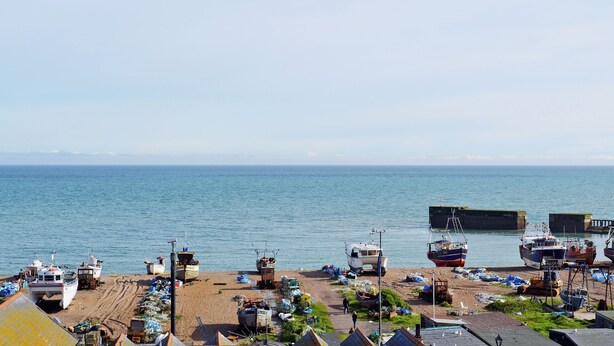 Eine Küstenlandschaft mit vertäuten Booten in der Nähe des Ufers, einem Sandstrand und freiem Blick auf das Meer.