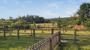 A fenced outdoor area with grass and trees, a wooden fence, and a wooden post with a yellow bucket. - 1 bedroom accommodation in Charfield, near Wotton-under-Edge (Charfield, near Wotton-under-Edge)