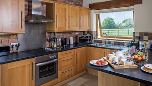 A kitchen with wooden cabinets, stainless steel appliances, and a large window with a view of the outdoors. - 1 bedroom accommodation in Charfield, near Wotton-under-Edge (Charfield, near Wotton-under-Edge)