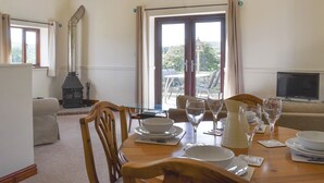 A dining area with a table set for four, a fireplace, and a television. - 2 bedroom accommodation in Thorncombe, near Broadwindsor (Thorncombe, near Broadwindsor)