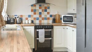 Una cocina moderna con estufa, horno, microondas y un salpicadero de azulejos.