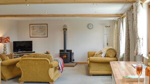 Una sala de estar acogedora con dos sofás, una chimenea, un televisor y un comedor con mesa y sillas.
