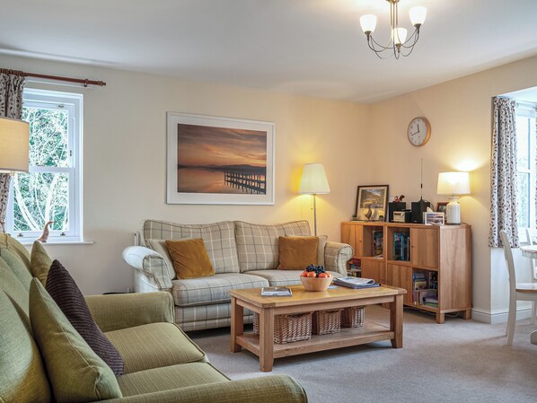 A living room with a sofa, a coffee table, a lamp, a bookshelf, and a painting on the wall.