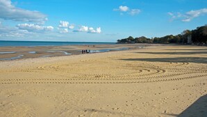 A wide sandy beach with footprints and a clear sky.