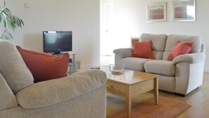 A living room with a television, two sofas, a coffee table, and a lamp.